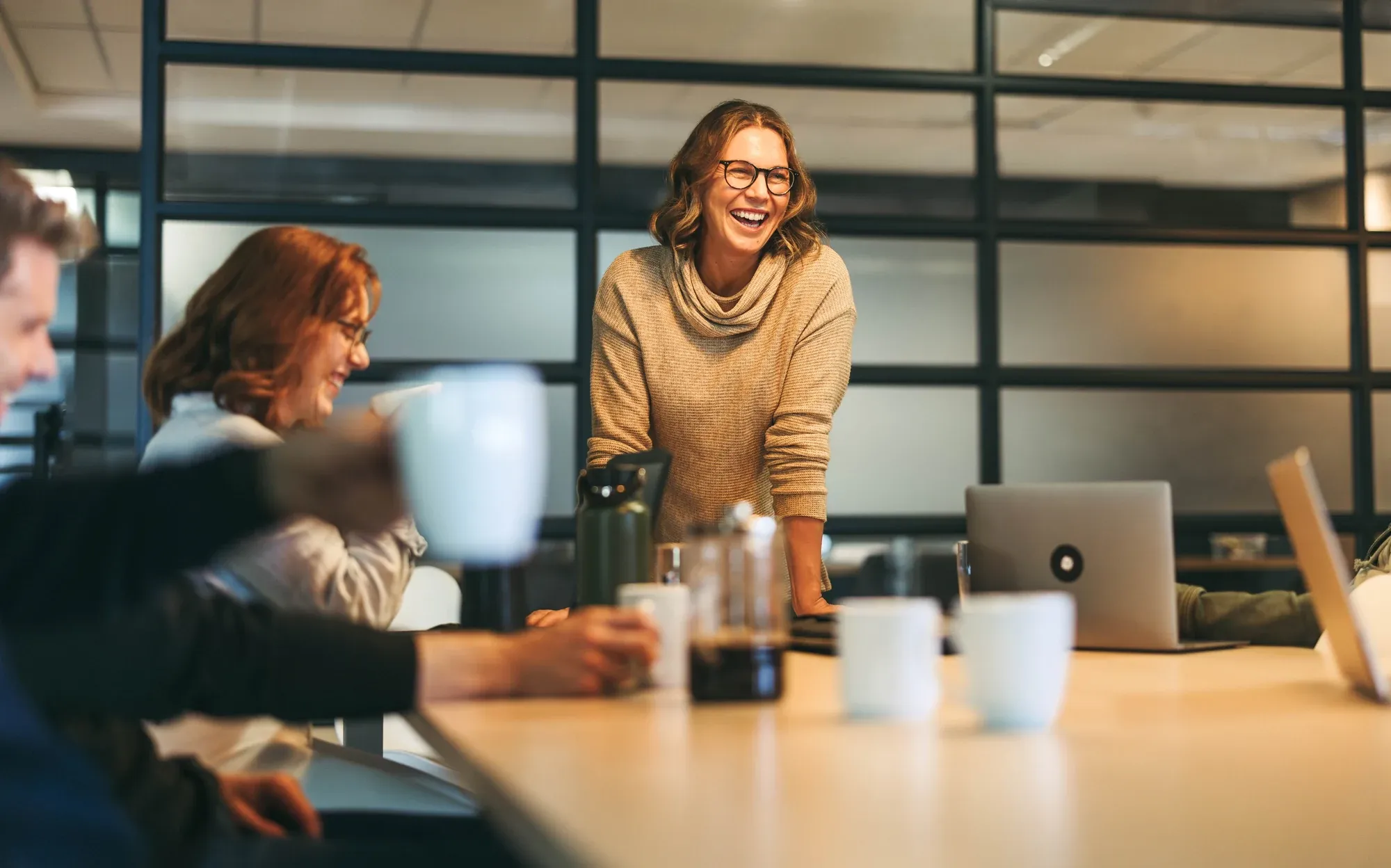 A board member laughing as she leads a discussion across the table