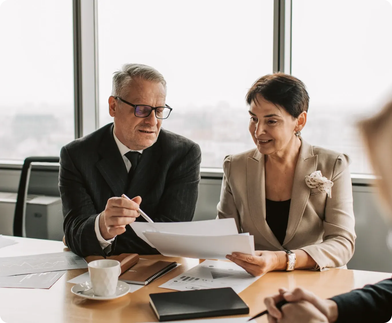 Two business owners reviewing documents at a boardroom table